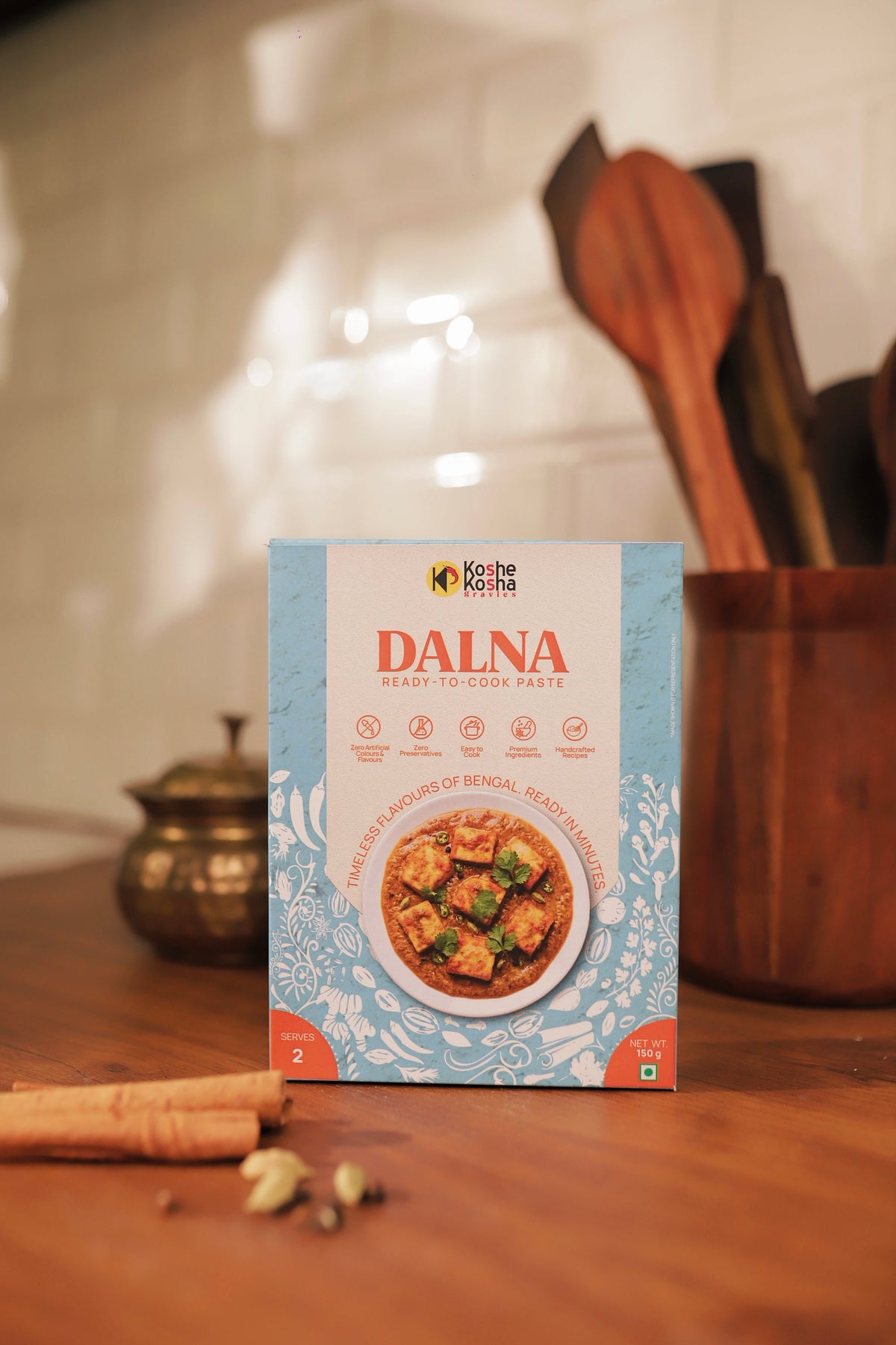 Dalna box on a wooden counter with a brass pot, cinnamon and wooden spoons