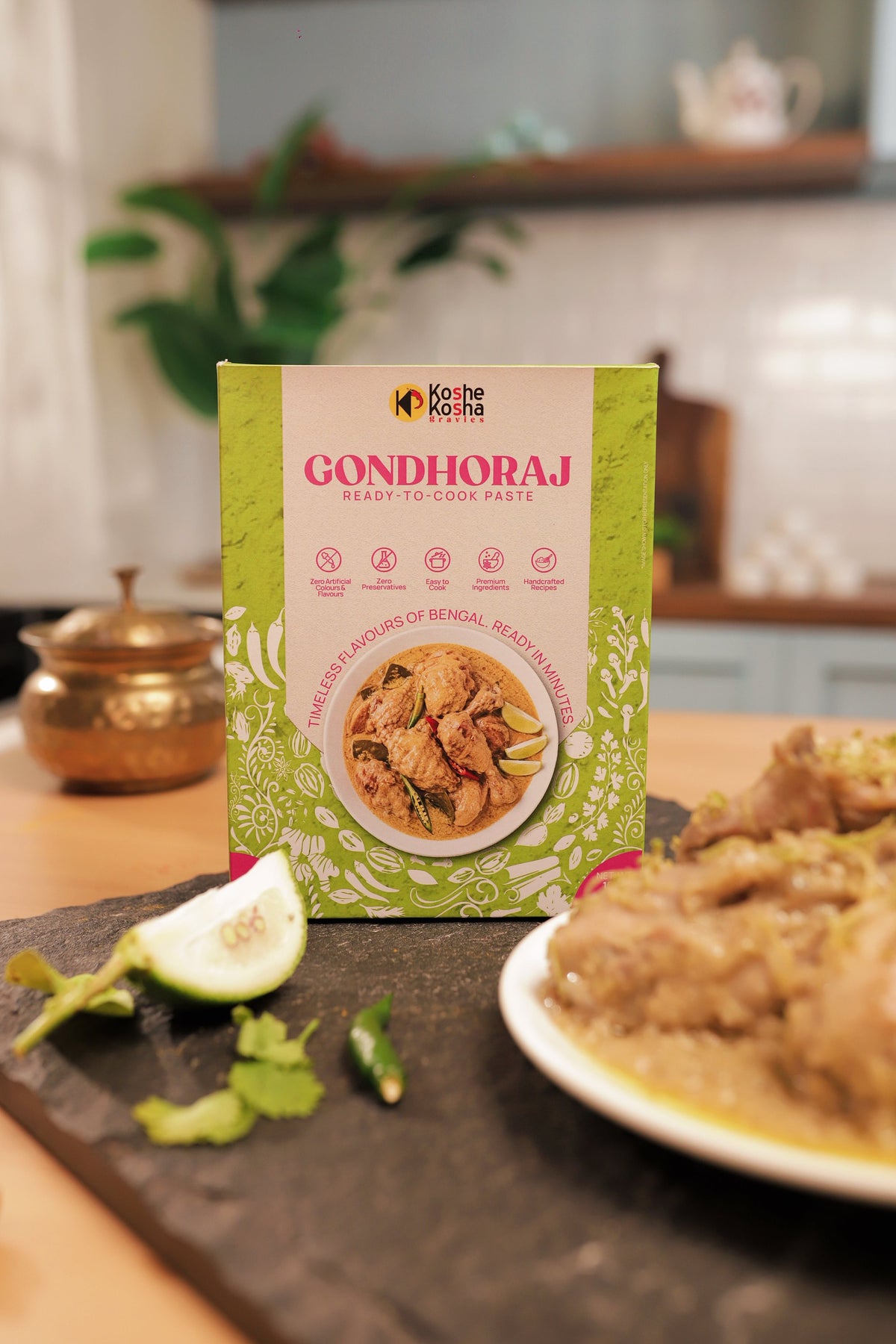 Gondhoraj box beside gondhoraj chicken, a lemon wedge and coriander on slate in a home kitchen