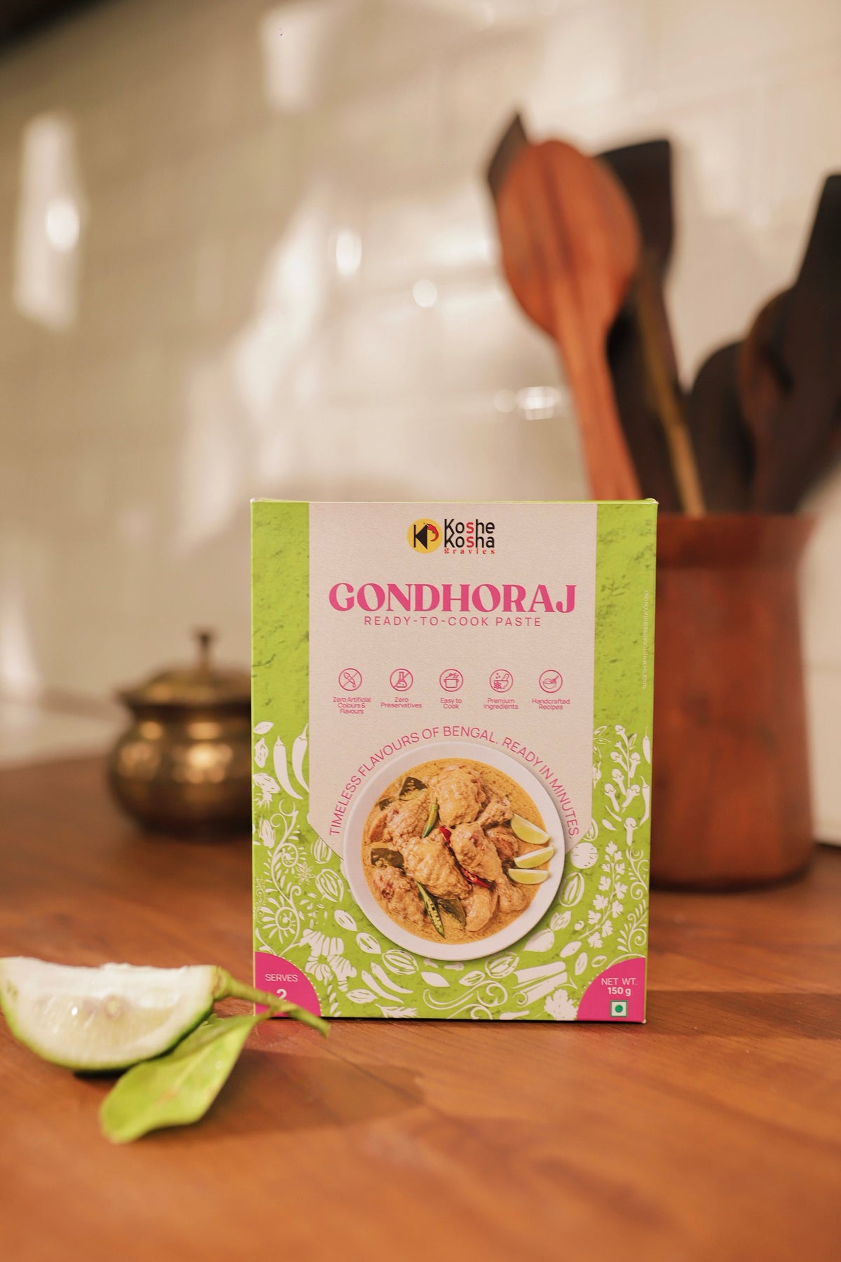 Gondhoraj box on a wooden counter with a lemon wedge and wooden spoons