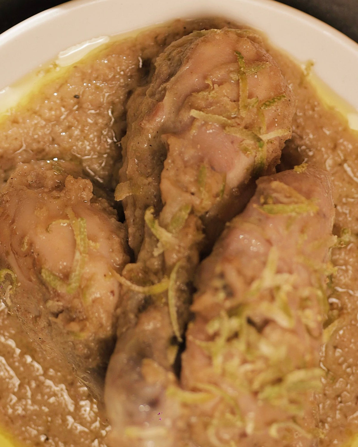 Close-up of chicken in pale Gondhoraj gravy with grated lemon zest