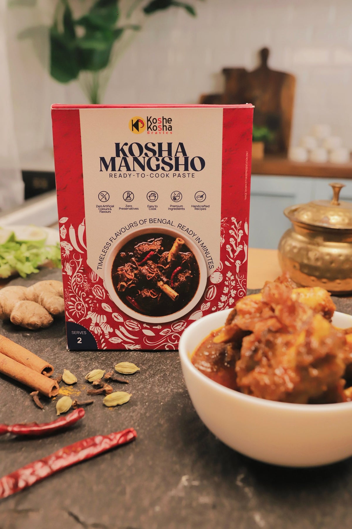 Kosha Mangsho box with mutton kosha, ginger, cinnamon, cardamom and dried red chillies on a kitchen counter