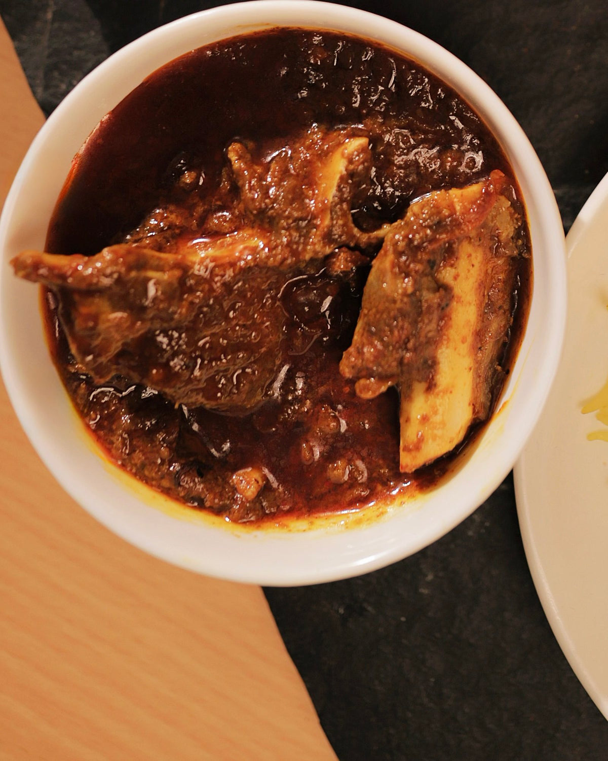 Top-down close-up of a bowl of dark, slow-cooked kosha mangsho